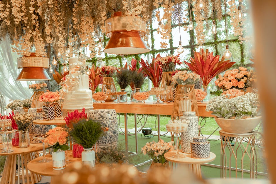 A floral arrangement display featuring a variety of fresh flowers and plants, including large pink protea, white roses, delicate white baby's breath, and vibrant pink and red blossoms. The flowers are